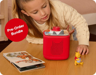Child playing with a red Toniebox on a table, with a Winnie the Pooh bear.